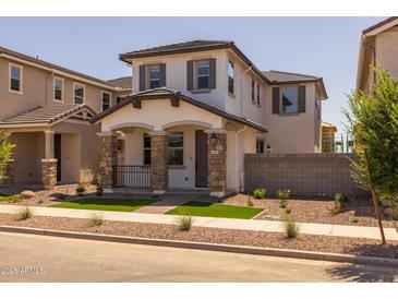 Charming two-story home featuring a cozy front porch with stone accents and a well-manicured front yard at 13465 N 158Th Ave, Surprise, AZ 85379