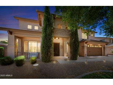 Inviting two-story home with meticulously landscaped front yard and charming architectural details at twilight at 2541 E Carob Dr, Gilbert, AZ 85298