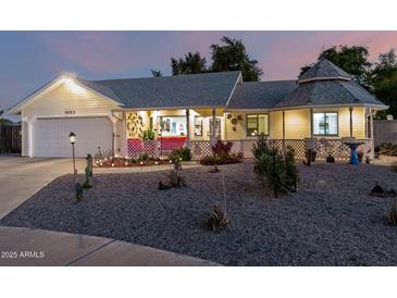 Charming single-story home with a well-maintained lawn, unique gazebo, and inviting front porch at twilight at 4013 E Delta Cir, Mesa, AZ 85206