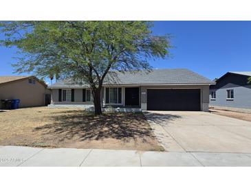 Charming single-story home featuring a well-maintained front yard with mature tree and a two-car garage at 8936 W Mackenzie Dr, Phoenix, AZ 85037