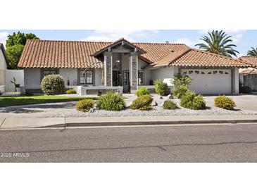 Charming single-story home showcasing a red tile roof, landscaped front yard, and inviting stone entryway at 1015 E Paradise Ln, Phoenix, AZ 85022