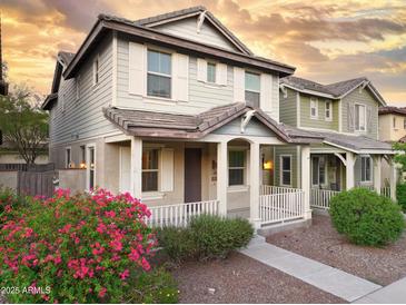 Charming two-story home featuring a cozy front porch, white railings, and beautiful, vibrant landscaping at 2947 N Evergreen St, Buckeye, AZ 85396