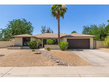 Charming single-story home featuring desert landscaping, a brick facade, and a two-car garage at 6417 E Kings Ave, Scottsdale, AZ 85254