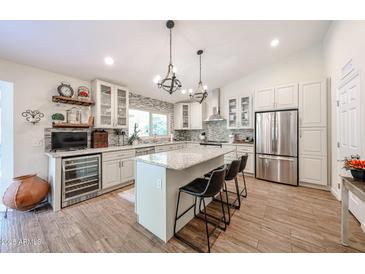 Bright, open kitchen with large island, stainless steel appliances, wine cooler and custom cabinetry at 9085 E Windrose Dr, Scottsdale, AZ 85260