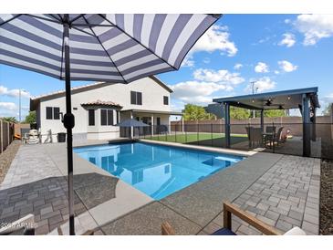 Beautiful backyard with a pool, patio umbrella, covered patio, and outdoor dining area at 19002 N 25Th Pl, Phoenix, AZ 85050