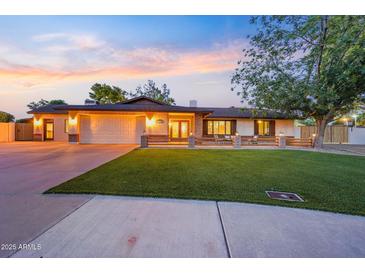 Charming single-story home with a well-manicured lawn and a two-car garage at sunset at 14221 N 43Rd St, Phoenix, AZ 85032
