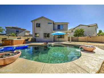 Stunning backyard pool with a hot tub and an umbrella in a low-maintenance backyard at 14719 N 176Th Ave, Surprise, AZ 85388