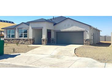 Charming single-story home with a stone facade, two-car garage, and a well-maintained desert landscape at 1540 E Mason Dr, Casa Grande, AZ 85122
