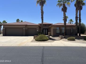 Beautiful single-story home featuring a lush landscaped front yard and a spacious three-car garage at 20332 N Denizen Dr, Surprise, AZ 85387