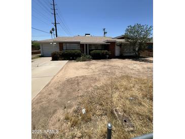 Single level brick home with attached garage and dry landscaping in need of renovation at 3701 W Keim Dr, Phoenix, AZ 85019