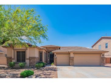 Beautiful single-story home featuring a well-maintained front yard, desert landscaping and a 3-car garage at 26072 N 74Th Ave, Peoria, AZ 85383