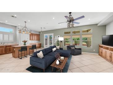 An inviting living room boasts a comfortable blue sectional sofa, an elegant chandelier, and tile flooring at 26135 N Desert Mesa Dr, Surprise, AZ 85387