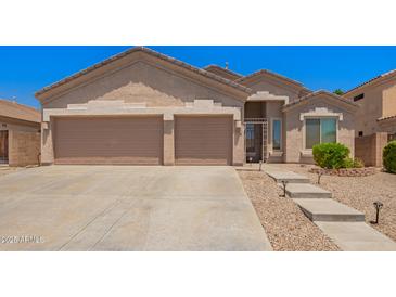 A home with a spacious three car garage and desert landscaping in front at 9142 W Pontiac Dr, Peoria, AZ 85382