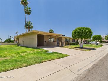 Charming single-story home boasting lush green lawn, mature landscaping, and a covered carport at 9915 W Mountain View Rd, Sun City, AZ 85351