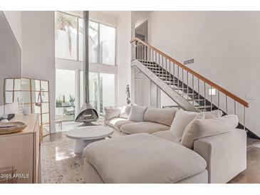 Bright living room featuring modern fireplace, staircase to loft, large windows, and comfortable neutral furniture at 930 S Dobson Rd # 3, Mesa, AZ 85202