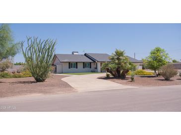 Charming single story home featuring a paved driveway, a dark roof, and mature landscaping at 5102 W Whispering Wind Dr, Glendale, AZ 85310