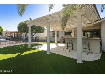 Inviting backyard features a covered patio, outdoor bar, and lush artificial grass at 922 S Ember Cir, Mesa, AZ 85208