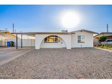 Charming single-story home featuring white exterior, rock landscaping, covered parking, and arched entry at 2508 N 58Th Ln, Phoenix, AZ 85035