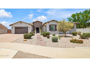 Inviting single-story home with a three-car garage, desert landscaping, and stone walkway at 23090 S 201St St, Queen Creek, AZ 85142