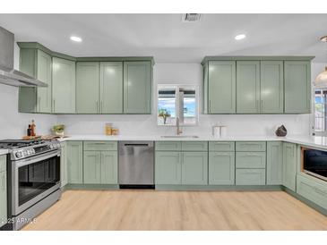 Modern kitchen featuring light green cabinets, stainless steel appliances, and light hardwood floors at 2712 N 20Th Dr, Phoenix, AZ 85009