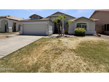 Charming home featuring a two-car garage, and mature landscaping with palm trees at 317 E Nunneley Rd, Gilbert, AZ 85296