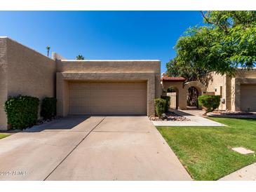 Beige home showcasing an attached two-car garage, desert landscaping and an arched doorway at 2059 E Brown Rd # 35, Mesa, AZ 85213