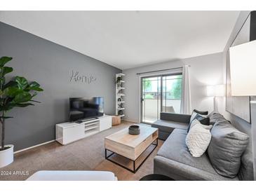 Comfortable living room features gray walls, modern furniture, and sliding glass door to patio at 357 E Thomas Rd # A208, Phoenix, AZ 85012