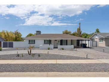 Charming single-story home featuring a well-manicured front yard, stylish gray brick driveway, and freshly painted white exterior at 3814 N 36Th St, Phoenix, AZ 85018