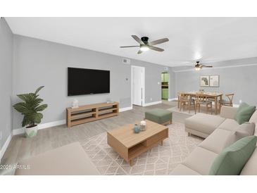 Open-concept living room and dining area featuring hardwood floors, modern furniture, and ceiling fans at 3825 E Camelback Rd # 182, Phoenix, AZ 85018