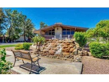 Charming home exterior with a unique rock waterfall feature and mature trees at 1550 N Stapley Dr # 95, Mesa, AZ 85203