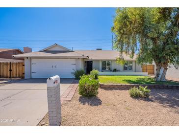 Charming single-story home featuring a well-maintained front yard with mature trees and a white mailbox at 17634 N 34Th Ln, Phoenix, AZ 85053