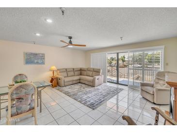 Bright living room with neutral tones, tiled floors, ceiling fan, and a door to the outside balcony at 453 S Parkcrest -- # 416, Mesa, AZ 85206