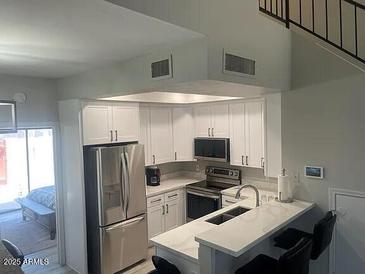 Bright kitchen featuring white cabinets, stainless steel appliances, and a convenient breakfast bar at 500 N Roosevelt Ave # 53, Chandler, AZ 85226
