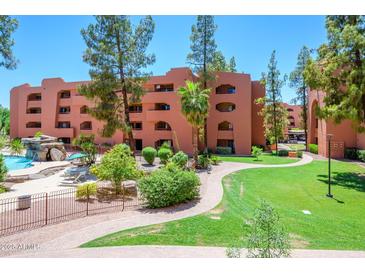 Beautiful condo complex exterior featuring lush landscaping and a community pool with a waterfall feature at 12222 N Paradise Village S Pkwy # 220, Phoenix, AZ 85032