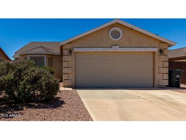 Beige exterior showing the two car garage and desert landscaping and blue sky at 1719 E Sandalwood Rd, Casa Grande, AZ 85122