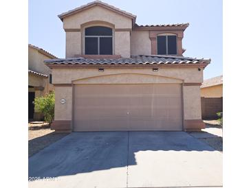 Beige two-story home featuring a two-car garage and a well-maintained concrete driveway at 1902 N 106Th Ave, Avondale, AZ 85392