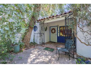 Charming front entrance with a decorative wreath, iron gate, and mature landscaping at 3303 E Clarendon Ave, Phoenix, AZ 85018