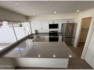 Beautiful kitchen with new stainless steel appliances and breakfast bar featuring grey countertops at 4849 W Northern Ave, Glendale, AZ 85301