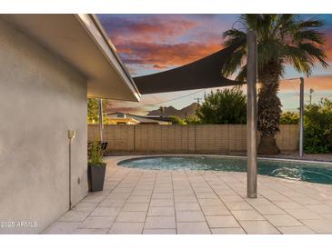 Inviting pool area with covered patio and lush landscaping at sunset at 7030 E Orange Blossom Ln, Paradise Valley, AZ 85253