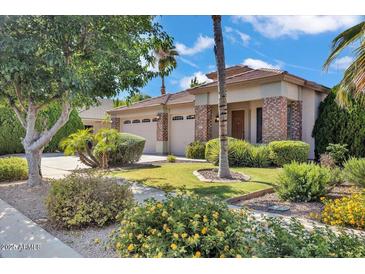 Landscaped front yard featuring mature trees and a well-maintained lawn and a circular driveway at 8820 W Glenn Dr, Glendale, AZ 85305