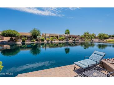 Picturesque backyard view with waterfront, lounge chairs, and lovely home exteriors on a sunny day at 20119 N Laguna Way, Maricopa, AZ 85138