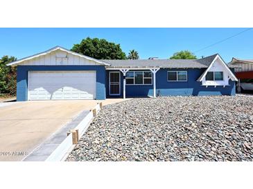 Charming blue single-story home with white trim, a stone yard, and a well-maintained front yard at 3202 W Joan De Arc W Ave, Phoenix, AZ 85029