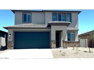 Two-story home featuring a two-car garage, neutral stucco exterior, and a covered front entryway at 5669 S 253Rd Ave, Buckeye, AZ 85326