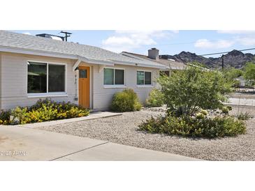Charming single-story home with a light-colored exterior, desert landscaping, and mountain views at 912 E Orchid Ln, Phoenix, AZ 85020