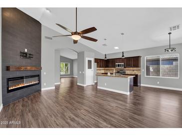 Inviting living room featuring a modern fireplace, ceiling fan, and an open view to the kitchen at 1332 W Blue Ridge Ct, Chandler, AZ 85248
