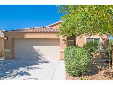 Single-story home featuring a two car garage, tile roof, desert landscaping, and a covered front porch at 8744 W Superior Ave, Tolleson, AZ 85353