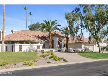Stunning home with a tile roof, meticulously landscaped front yard, and a grand entrance with palm trees at 10300 N 48Th Pl, Paradise Valley, AZ 85253