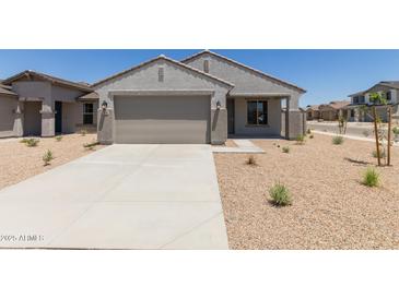 Charming single-story home featuring neutral stucco, a two-car garage, and desert landscaping on a sunny day at 18340 W Patrick Ln, Surprise, AZ 85387