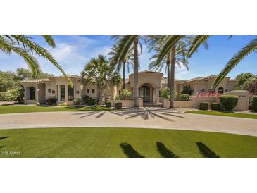 An elegant stucco home with a circular driveway, palm trees, and manicured landscaping provides a grand entrance at 6305 E Arabian Way, Paradise Valley, AZ 85253