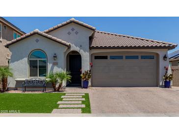 Charming single-story home featuring a tile roof, arched window, desert landscaping and a brick driveway at 15276 W Latham St, Goodyear, AZ 85338